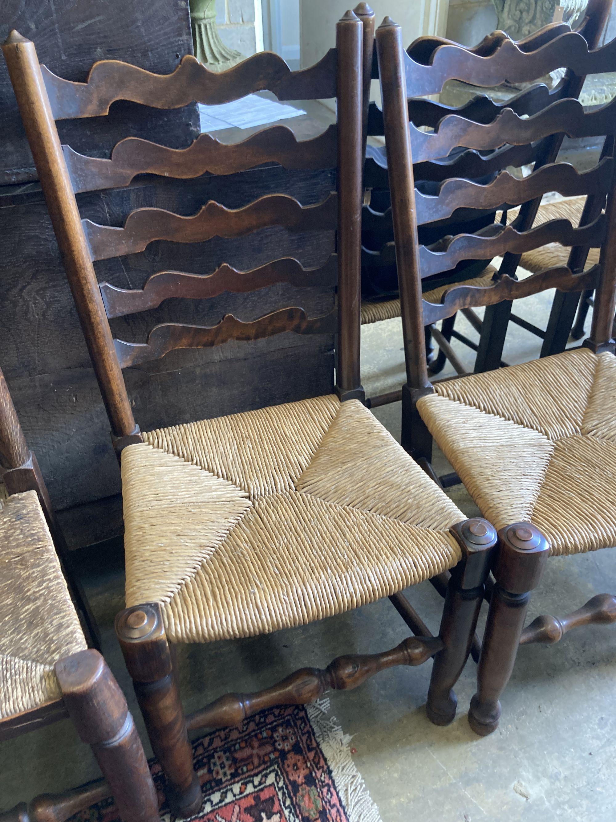 A harlequin set of seven oak and beech rush seated, ladder back dining chairs